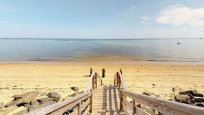 A wooden pier leading to a sandy beach with calm water and a clear sky. - Cheerful condo with enclosed porch, next to Cape Cod Bay with beach access (Provincetown)