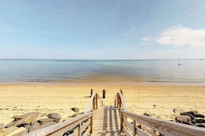 A wooden pier leading to a sandy beach with calm water and a clear sky. - Cheerful condo with enclosed porch, next to Cape Cod Bay with beach access (Provincetown)