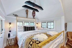 Ein Schlafzimmer mit einem großen Bett, Nachttischlampen, einem kleinen Tisch und einem Sessel.