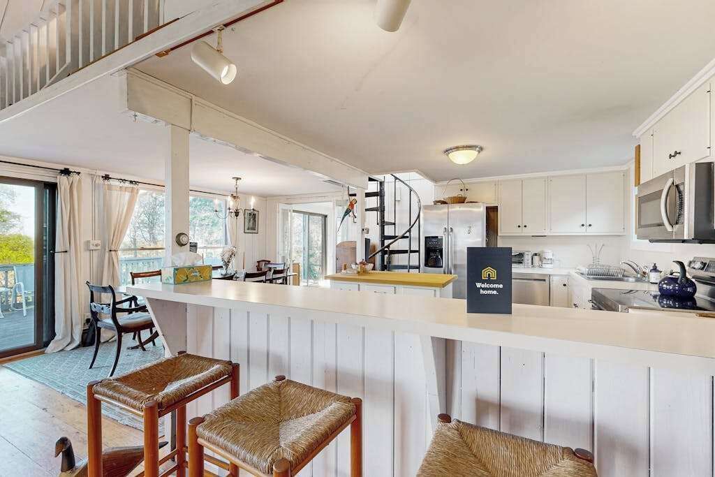 Une cuisine moderne avec des meubles blancs, un îlot central et un panneau indiquant : « Bienvenue chez vous. »