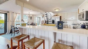 Une cuisine moderne avec des meubles blancs, un îlot central et un panneau indiquant : « Bienvenue chez vous. »