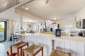 A modern kitchen with white cabinets, a central island, and a sign reading 'Welcome home.'