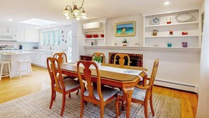 Una cucina moderna con mobili bianchi, un tavolo da pranzo con sedie, un lampadario e un camino con elementi decorativi.