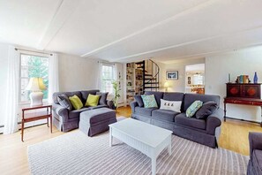 A living room with two grey sofas, a white coffee table, and a staircase leading to another room.