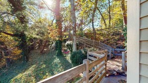 A wooden deck with a wooden railing, surrounded by trees and foliage. - Lakefront home with private dock, deck, & lovely view - short drive to the cape (Plymouth)
