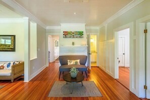 A hallway with a sofa, a fireplace, and a wooden floor. - Enchanting bungalow with golf nearby, full kitchen, central AC, & washer/dryer (Oak Bluffs)
