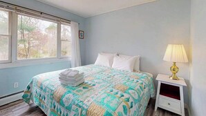Een slaapkamer met een bed, nachtkastje, lamp en raam.