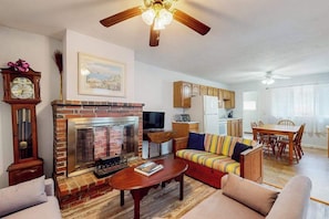 A living room with a fireplace, a sofa, a coffee table, and a dining area with a table and chairs.