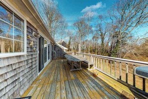A wooden deck with a bench and railing, overlooking a natural landscape.