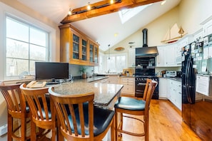 A kitchen with wooden cabinets, a large island, and a black stove.