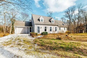 A two-story house with a garage, a covered porch, and a well-maintained lawn.