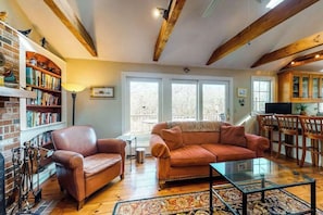 A cozy living room with a leather sofa, a glass coffee table, and a bookshelf.