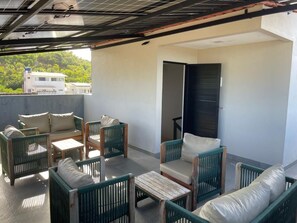 A balcony with wicker furniture, a door, and a view of buildings.