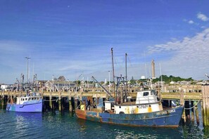 Un puerto con barcos amarrados a muelles de madera, cielo despejado y un edificio distante.