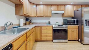 A kitchen with wooden cabinets, stainless steel appliances, a dishwasher, and a microwave. - Comfortable family getaway near the beach with patio, grill, WiFi and AC (West Yarmouth)
