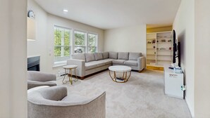 A modern living room with a sectional sofa, two armchairs, a coffee table, and a TV stand with shelves. - Comfortable family getaway near the beach with patio, grill, WiFi and AC (West Yarmouth)