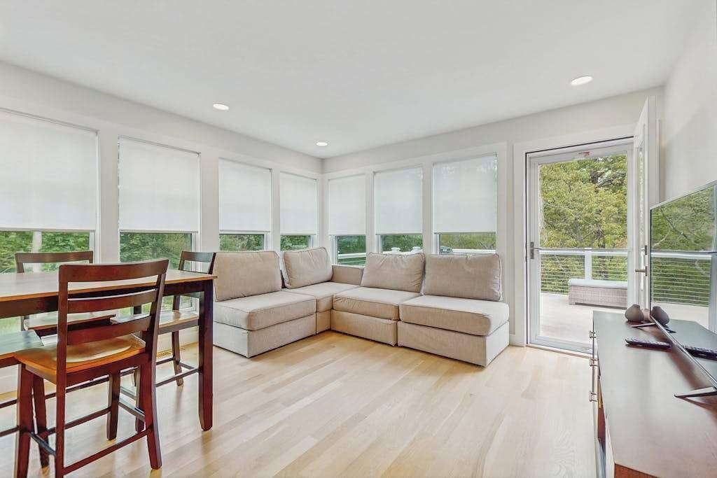 A modern living room with a sectional sofa, a dining table with chairs, and a TV.