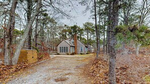 A house surrounded by trees with a gravel driveway. - Quiet home with sunroom, deck, W/D, AC, & quick access to beach (Wellfleet)