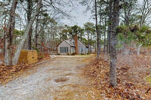 A house surrounded by trees with a gravel driveway. - Quiet home with sunroom, deck, W/D, AC, & quick access to beach (Wellfleet)