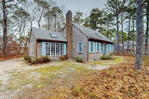 A rustic cabin with a chimney, large windows, and a stone foundation. - Quiet home with sunroom, deck, W/D, AC, & quick access to beach (Wellfleet)