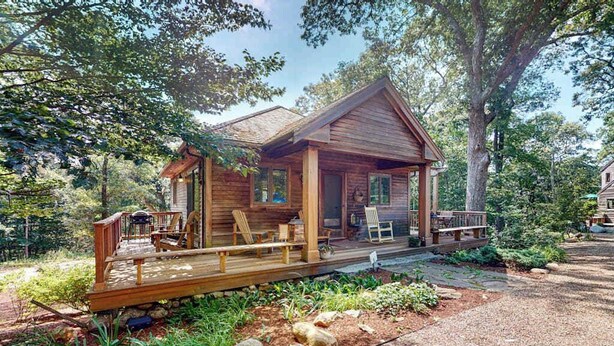 A wooden cabin with a porch, deck, and outdoor seating area surrounded by trees. - Nana’s Treehouse | House with spacious deck, grills, outdoor shower & W/D (West Tisbury)