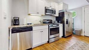 Una cocina moderna con armarios blancos, electrodomésticos de acero inoxidable y piso de madera.