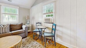 Una habitación con sofá, dos sillones, una mesita y una ventana con persianas.