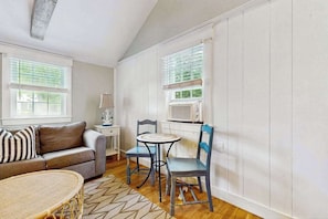 A room with a sofa, two chairs, a small table, and a window with blinds.