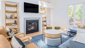 Ein modernes Wohnzimmer mit Kamin, Flachbildfernseher und großem Fenster.