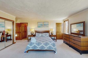 Een slaapkamer met een bed, een houten garderobe, nachtkastjes en een spiegel.