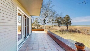 Varanda coberta com vista para um campo gramado e árvores.