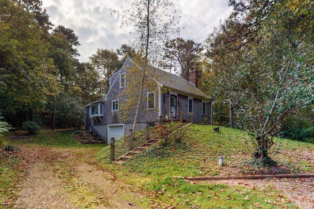 A house with a sloped roof, a front porch, and a driveway leading to a garage.