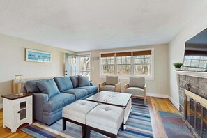 A living room with a sofa, chairs, a coffee table, a fireplace, and a window with blinds. - Peaceful Maravista escape with AC, W/D, yard, walk to Great Pond, & breezy charm (Falmouth)