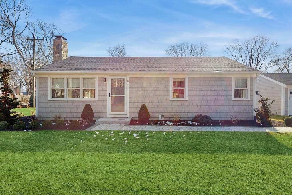 A single-story house with a brick exterior, a front door, and a small porch.