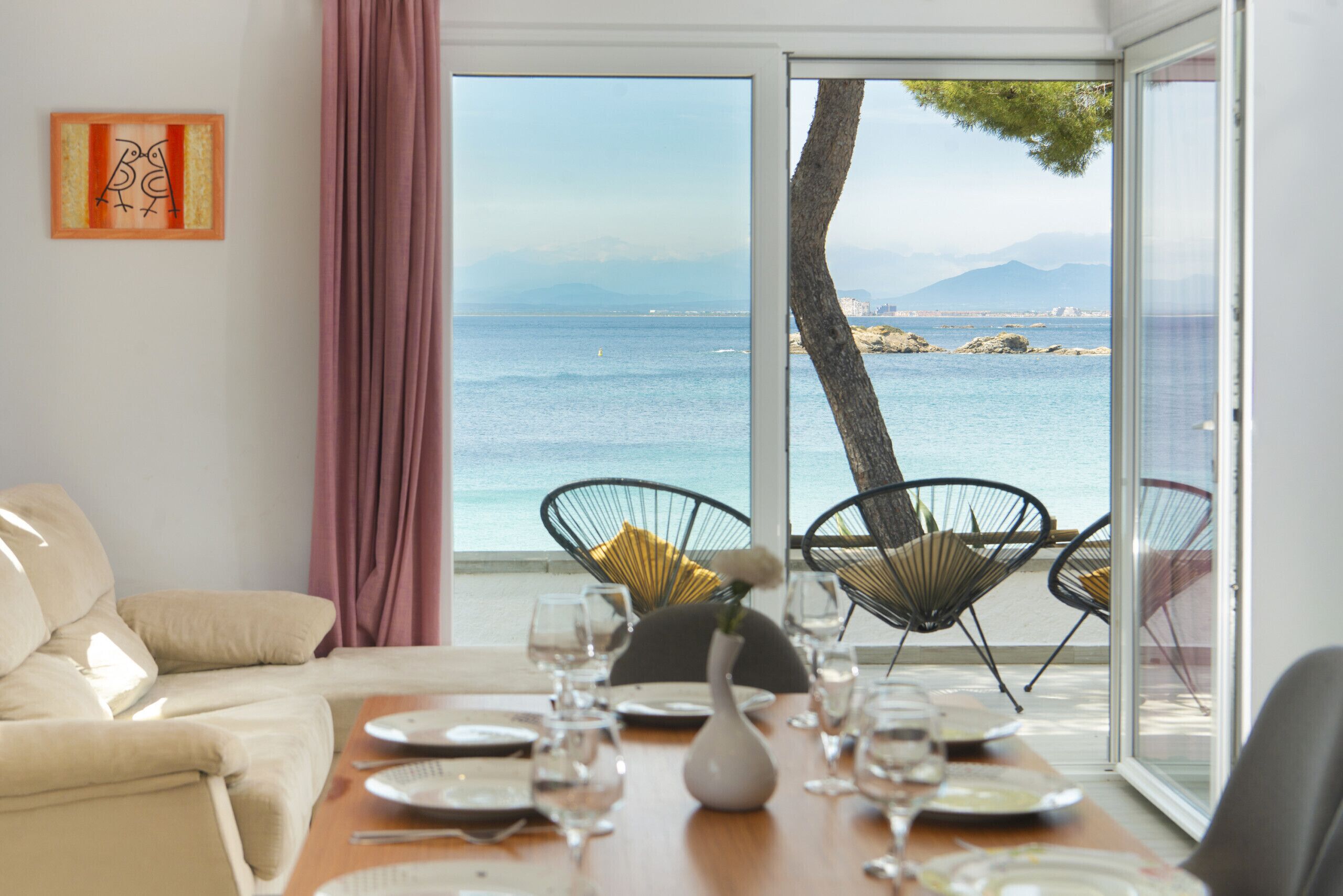 Comedor con vista al mar, un sofá y una mesa lista para dos.