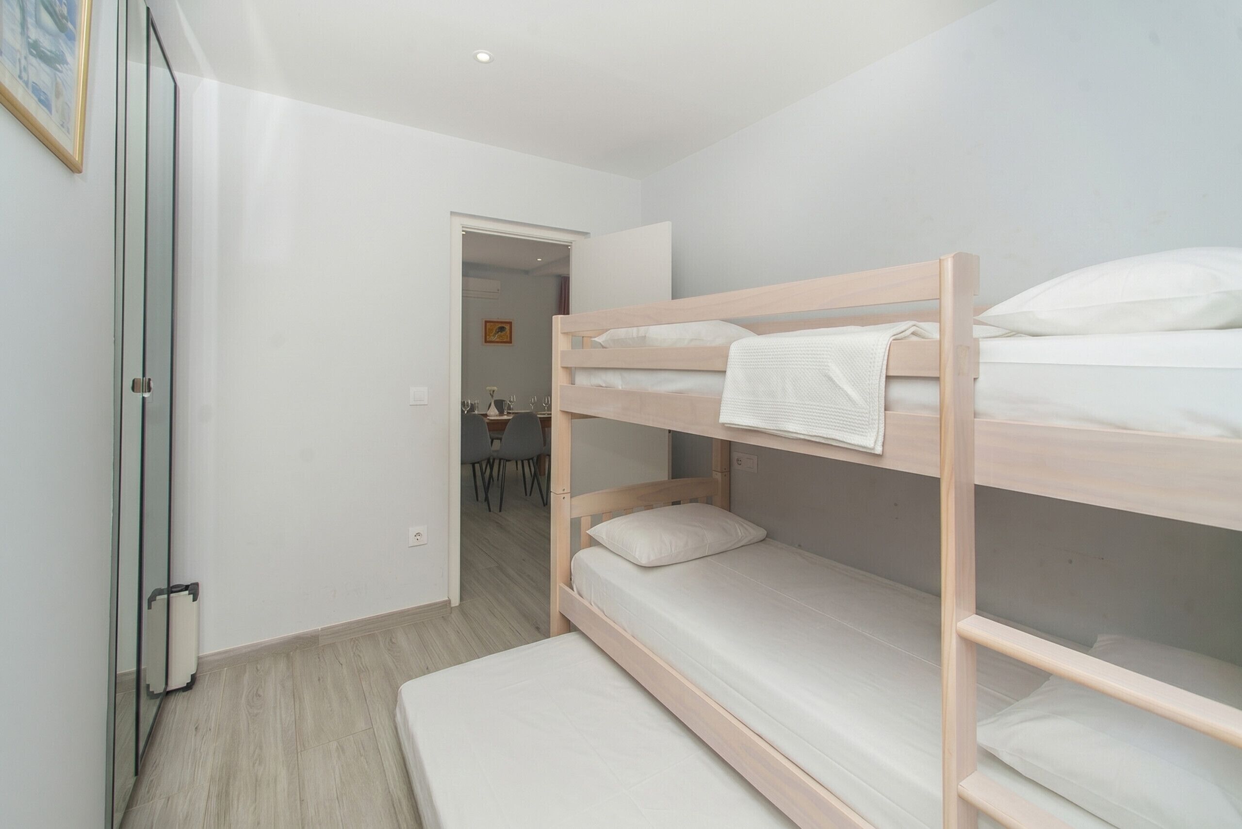 Een slaapkamer met een stapelbed met houten frame, een klein bureau en een stoel op de achtergrond.
