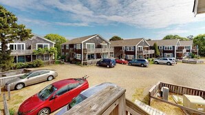 Un barrio residencial con varias casas de dos pisos, un camino de grava y automóviles estacionados.