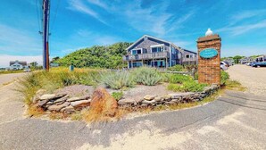 Un edificio de dos pisos con un balcón, un muro de piedra y un letrero que dice 'Bay Colony Condos'.