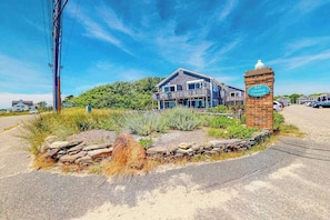 Un immeuble de deux étages doté d’un balcon, d’un mur en pierre et d’une enseigne indiquant « Bay Colony Condos ».