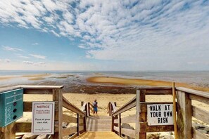 A wooden staircase leading to a beach with a sign warning of personal risk.