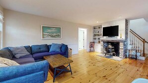 Un salon avec un canapé, une table basse en bois, une cheminée et un téléviseur.