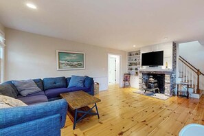Ein Wohnzimmer mit einer Couch, einem Holztisch, einem Kamin und einem Fernseher.