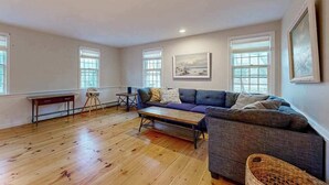 Un salon spacieux doté d’un parquet, d’un canapé, d’une table basse et d’une petite table avec des chaises.