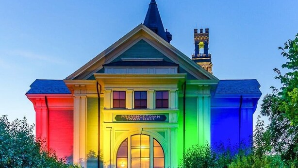 A building with a sign reading 'PROVINCTOWN TOWN HALL' and a steeple in the background.