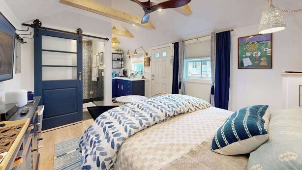 Een slaapkamer met een bed, een plafondventilator, een bureau en een kledingkast.