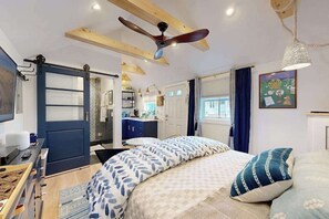 Une chambre à coucher comprenant un lit, un ventilateur de plafond, un bureau et une armoire.