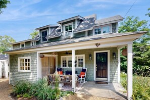 A two-story house with a porch, a front door, and a small window. - Updated house close to town and beach with patio, AC, and games (Oak Bluffs)
