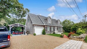 Une maison à deux étages avec une allée en gravier et un chemin de pierre menant à la porte d’entrée.
