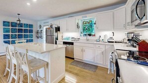 Une cuisine moderne avec des meubles blancs, un îlot central et un coin repas avec des chaises.