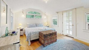 Une chambre à coucher avec un lit, une commode, une fenêtre et une porte.
